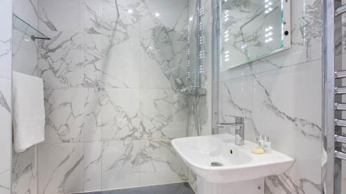 W białej łazience znajduje się umywalka i lustro. w obiekcie Castle House - Polruan w mieście Polruan