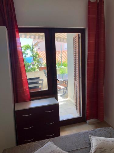 een slaapkamer met een dressoir en een glazen schuifdeur bij Apartmani Gloria in Brodarica