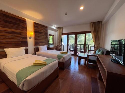 Habitación de hotel con 2 camas y TV en Phuket Meet Holiday Hotel 普吉岛相遇酒店, en Rawai Beach