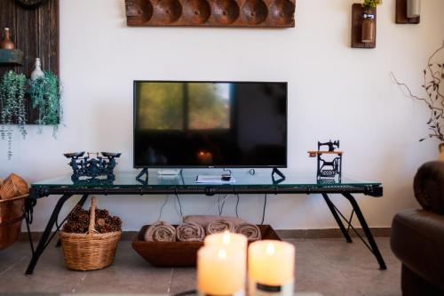 een woonkamer met een televisie op een tafel met kaarsen bij Stella's Country House in Prodromos