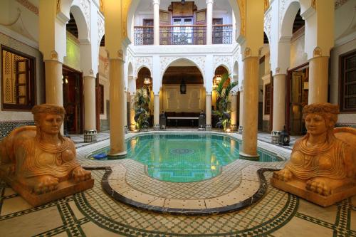 een zwembad in een gebouw met beelden eromheen bij Riad Esmeralda in Marrakesh