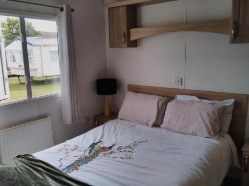 a bed in a bedroom with a window at Private caravan situated at Parkdean Holiday Resort St Margaret's at Cliffe number 18 in St Margarets at Cliff