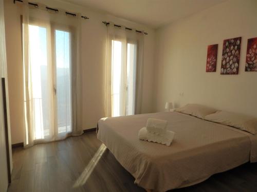 a bedroom with a bed with white sheets and windows at Casa Foddis - Bed and View in Baunei