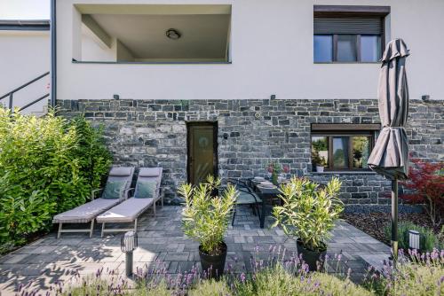 a patio with two chairs and an umbrella at Nádas Center Home Badacsony in Badacsonytomaj