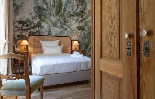 a bedroom with a bed and a chair and a door at Villa Bleichröder in Heringsdorf