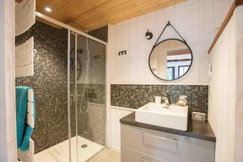 La salle de bains est pourvue d'un lavabo, d'une douche et d'un miroir. dans l'établissement Ma Cabane au Ferret à proximité de l'Océan, à Lège-Cap-Ferret