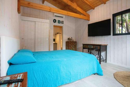 una camera con letto blu e TV a schermo piatto di Ma Cabane au Ferret à proximité de l'Océan a Lège-Cap-Ferret