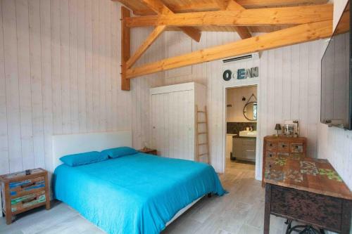 a bedroom with a blue bed and a bathroom at Ma Cabane au Ferret à proximité de l'Océan in Lège-Cap-Ferret