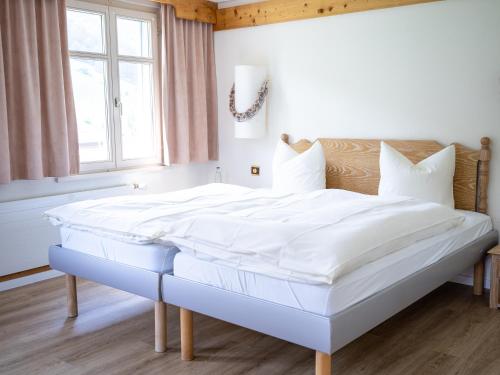 a large white bed in a room with a window at Hotel Sternen Unterwasser in Unterwasser