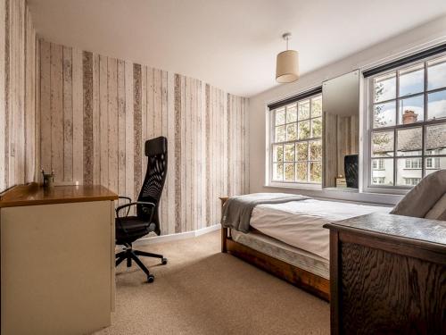 1 dormitorio con cama, escritorio y silla en Pass the Keys Stylish family home central Topsham with parking en Exeter