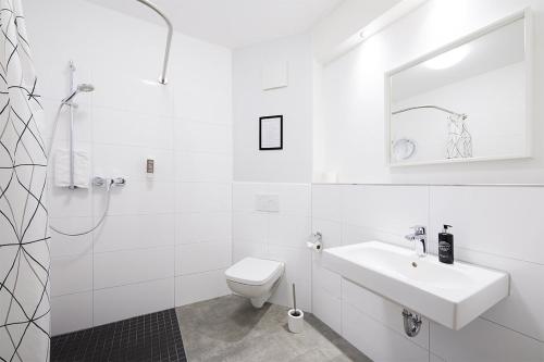 a white bathroom with a sink and a toilet at Hotel Sarah in Heinsberg