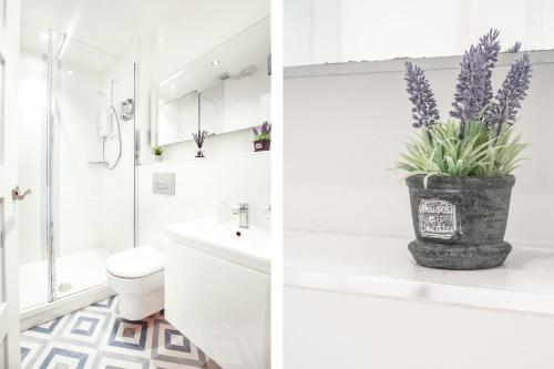 a white bathroom with a toilet and a vase with purple flowers at Perfect City Centre Location - Historic Albion Mews in Chester
