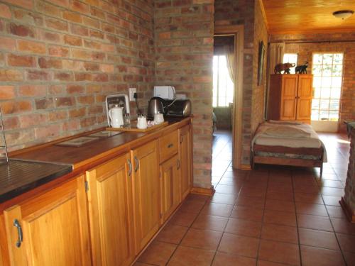 a kitchen with wooden cabinets and a brick wall at Thaba Tsweni Lodge & Safaris in Graskop