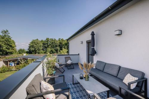 a rooftop patio with a couch and chairs at Nádas Center Home Badacsony in Badacsonytomaj