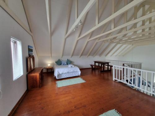 1 dormitorio con 1 cama y suelo de madera en The Dune Hideaway, en Port Alfred