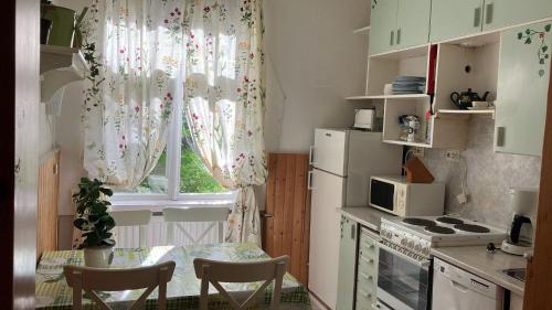 a kitchen with a table and a window with curtains at VILLA ANNA in Naantali