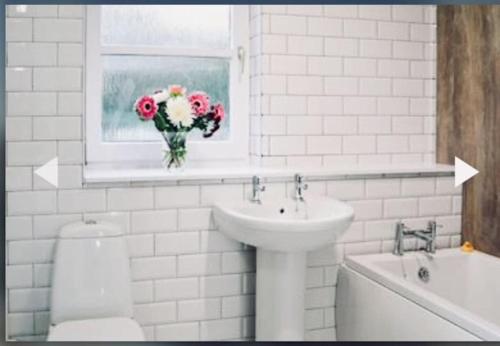 baño con lavabo, aseo y un jarrón de flores en 3 Bedroom harbourside apartment, Queensferry, 10 miles from Edinburgh, en Queensferry