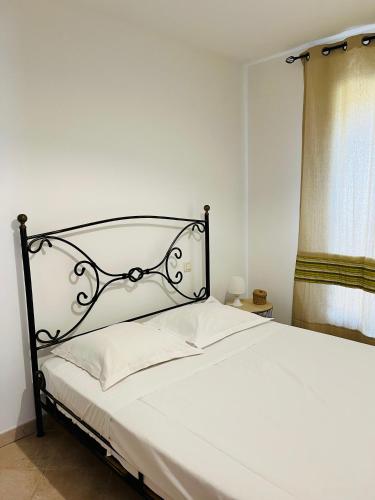 - une chambre avec un lit blanc et une tête de lit noire dans l'établissement Villa Acula Marina, à Lucciana