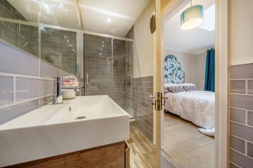a bathroom with a white sink and a bed at Stunning 3B2Ba Huge entertaining space and hottub! in Raynes Park