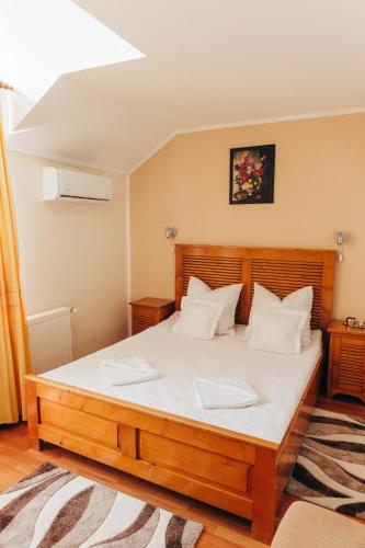 a bedroom with a large wooden bed with white pillows at Vila Carmen-camere de închiriat 3 stele in Baile Unu Mai