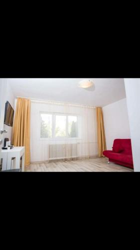 uma sala de estar com um sofá vermelho e uma janela em Apartament Tiffany em Cluj-Napoca