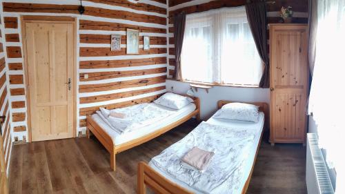 two beds in a room with wooden walls and windows at Wellness chata - Krkonoše in Rudník
