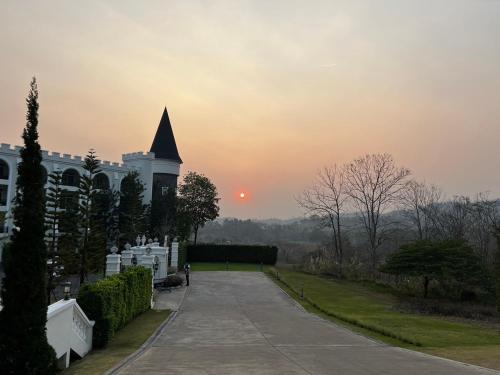 a building with a clock tower with a sunset in the background at Blue Sky Khao Kho Castell Condo in Campson