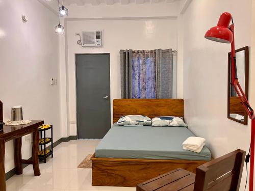 1 dormitorio con 1 cama y lámpara roja en FN Lodge - town proper, en Palompon