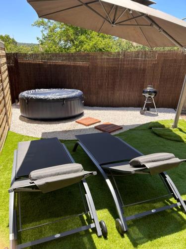 two chairs and an umbrella in a yard with a grill at La suite avec jacuzzi in Saint-Martin-de-Londres