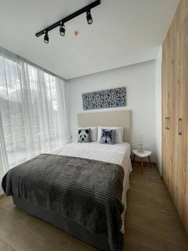 Un dormitorio blanco con una cama grande y una ventana en Lindo e iluminado apartaestudio en La Carolina, en Quito