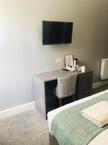 a hotel room with a desk with a television on the wall at Arrandale Guest House in Edinburgh