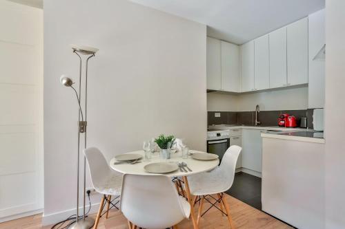 uma cozinha branca com mesa e cadeiras em Studio - Appartement Quartier Montparnasse 2 em Paris