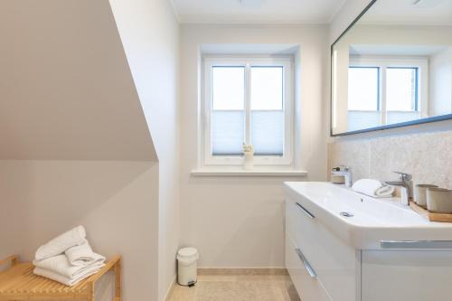 Un baño blanco con lavabo y espejo. en Biikehuus West, en Niebüll