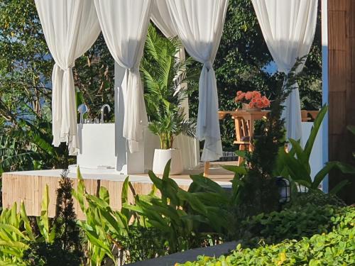 a garden with white curtains and plants at เฌอปือ เชียงใหม่ Cherpue Chiangmai in Ban Mae Na