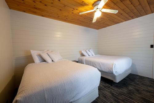 two beds in a room with a ceiling fan at Depe Dene Lakeside Resort in Lake George