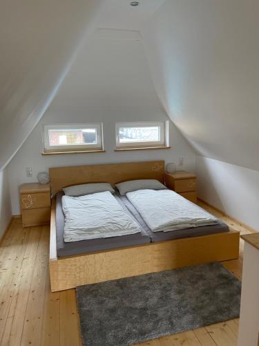 een slaapkamer met een bed en 2 ramen bij Ferienhaus Waldweg in Wienhausen