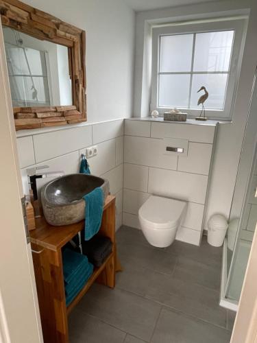 een badkamer met een wastafel, een toilet en een raam bij Ferienhaus Waldweg in Wienhausen