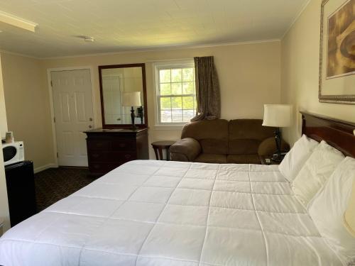 a bedroom with a large white bed and a couch at Villager Motel in Williamstown