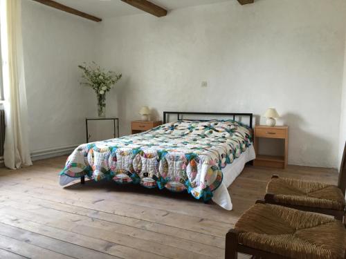 a bedroom with a bed and two tables and a chair at Maison du Bûcheron in Melay
