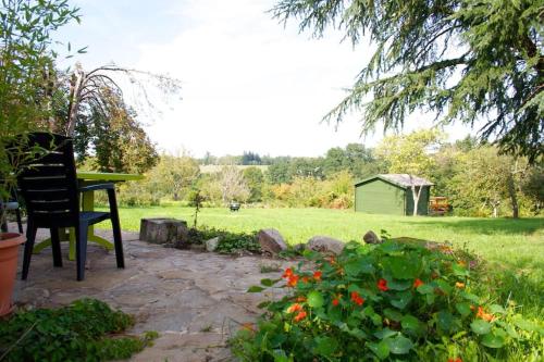 a patio with a chair and a table in a garden at The Piggery, charming converted stone gite in Saint-Mesmin