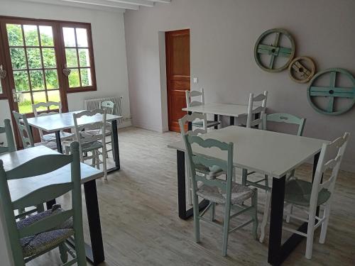 uma sala de jantar com mesas e cadeiras e um espelho em La maison de pescate em Souprosse