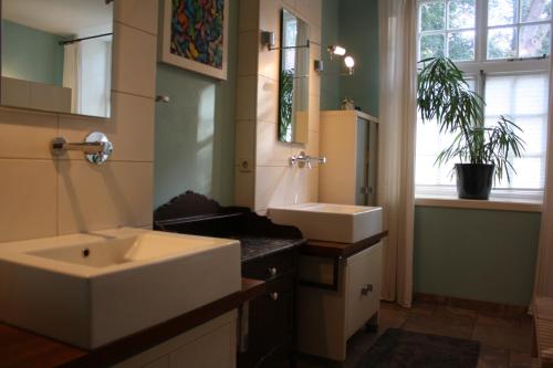 a bathroom with two sinks and a mirror and a window at Flett - Artlands Home - Landhaus für Familien und Gruppen in Badbergen