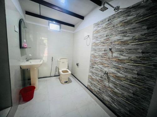 a bathroom with a toilet and a stone wall at Harini Villa in Sigiriya