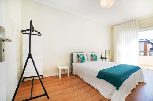 a white bedroom with a bed and a tripod at Casa da Avó Toninha by Quantique in Braga