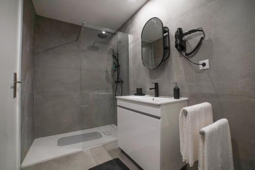 een badkamer met een wastafel, een douche en een spiegel bij Casa da Avó Toninha in Braga