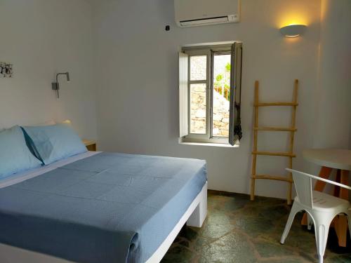 a bedroom with a bed and a chair and a window at Amorgos Elegant Houses, 6 Villas in Amorgos