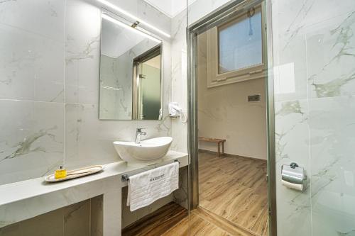 a white bathroom with a sink and a shower at Amoudi Studios Apartments Hotel in Amoudi