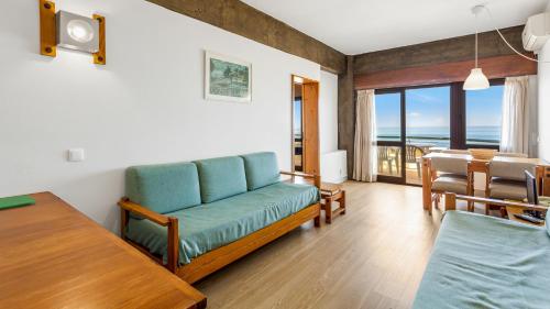 - un salon avec un canapé bleu et une table dans l'établissement 1BDR Apartment W/Beach View by LovelyStay, à Monte Gordo