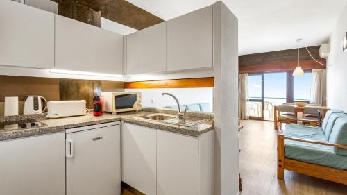 eine Küche mit einer Spüle und einer Mikrowelle in der Unterkunft 1BDR Apartment W/Beach View by LovelyStay in Monte Gordo