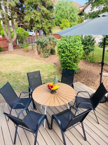 a table with chairs and a bowl of fruit on a deck at Altmuehl Familienvilla in Treuchtlingen